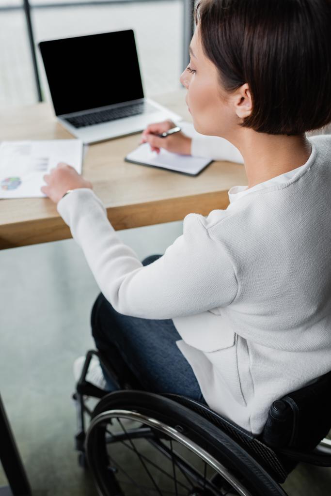 Ofisinde boş ekranla bulanık dizüstü bilgisayarda çalışan engelli bir iş kadını. - Fotoğraf, Görsel