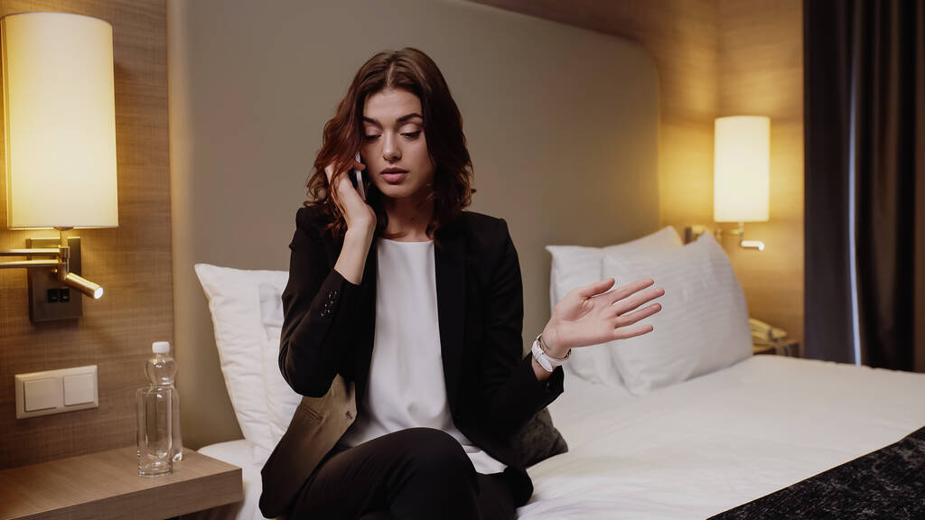Tätowierte und unzufriedene Geschäftsfrau spricht auf Smartphone im Hotelzimmer - Foto, Bild