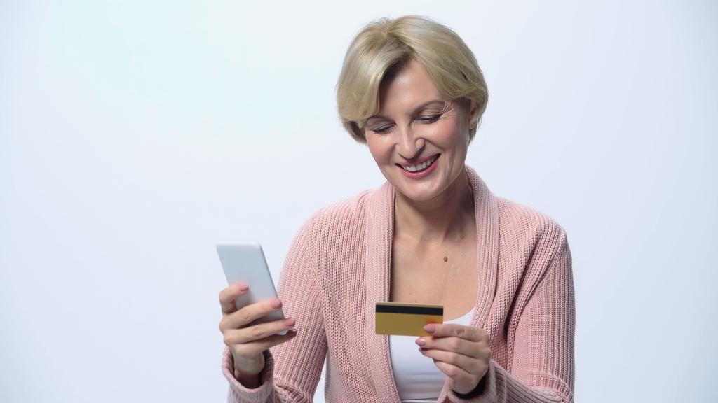boldog középkorú nő nézi hitelkártya használata közben okostelefon elszigetelt fehér - Fotó, kép