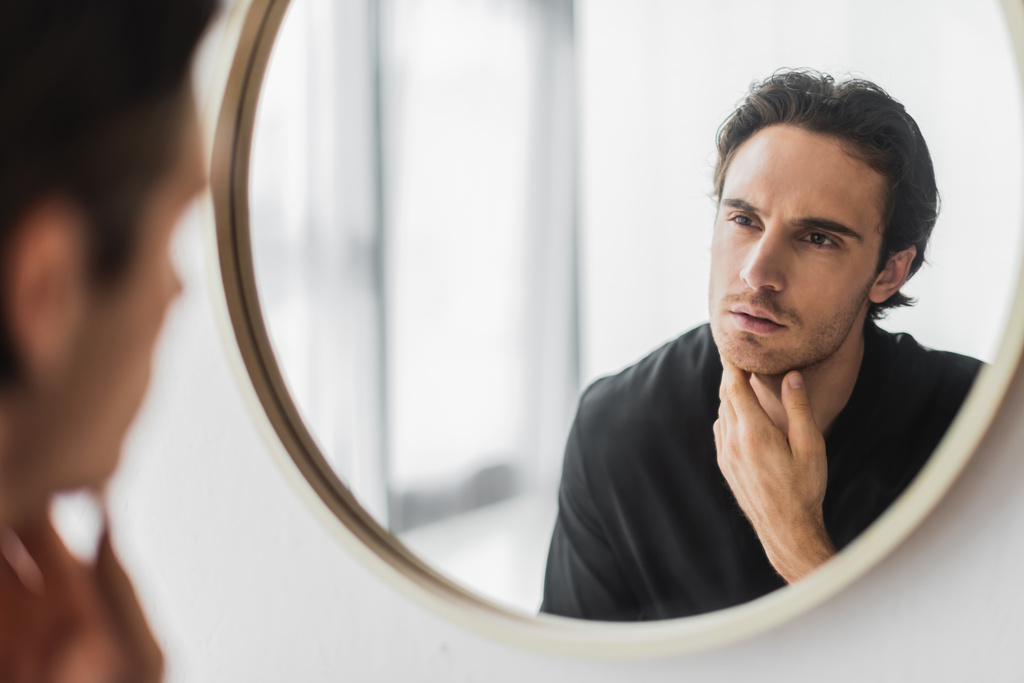 wazige man in zwart gewaad kijkend naar spiegel thuis  - Foto, afbeelding