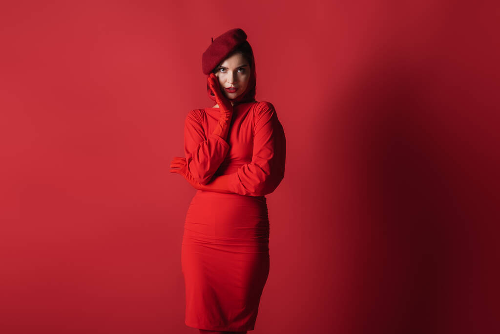 nuori tyylikäs nainen baskeri ja mekko poseeraa katsellessaan kameran punainen - Valokuva, kuva