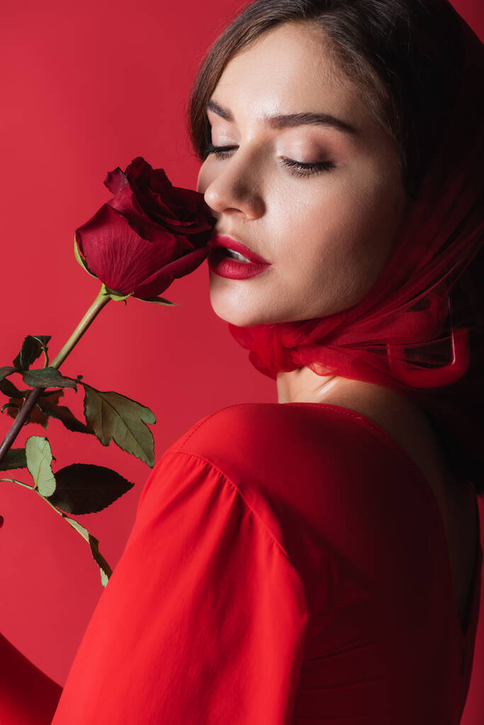 Nuori nainen huivi tuoksuva ruusu eristetty punainen - Valokuva, kuva