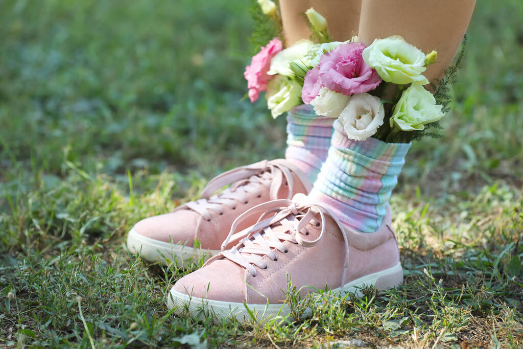 Mujer de pie sobre hierba verde con flores en calcetines, primer plano - Foto, Imagen