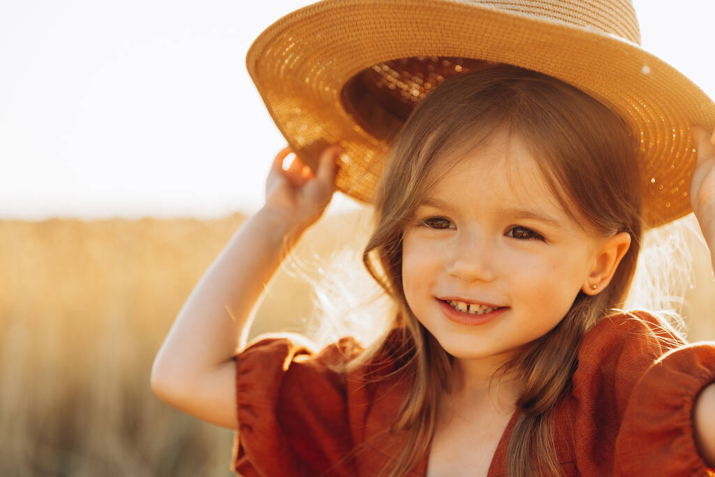 Pieni kaunis hymyilevä tyttö kultaisella vehnäpellolla. Tytöt viljapellolla. Söpö pikkutyttö vehnäpellolla.  - Valokuva, kuva