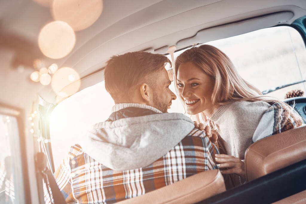 Οπίσθια άποψη του όμορφου νεαρού ζευγαριού απολαμβάνοντας οδικό ταξίδι μαζί, ενώ κάθεται στις μπροστινές θέσεις του minivan - Φωτογραφία, εικόνα