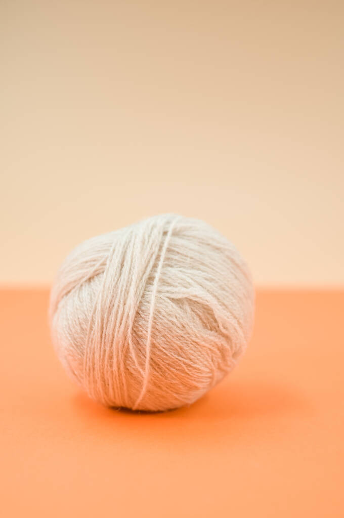 A vertical shot of isolated beige yarn on a yellow background with text space - Photo, Image
