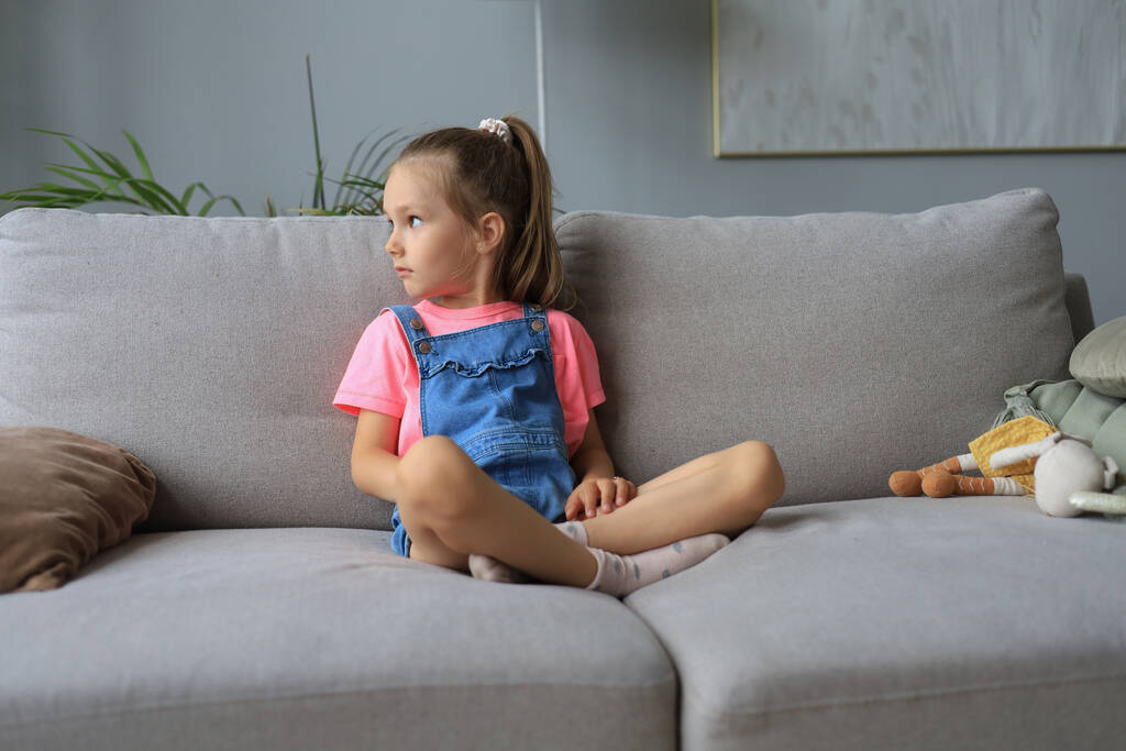 Triste bambina seduta sul divano da sola a casa - Foto, immagini