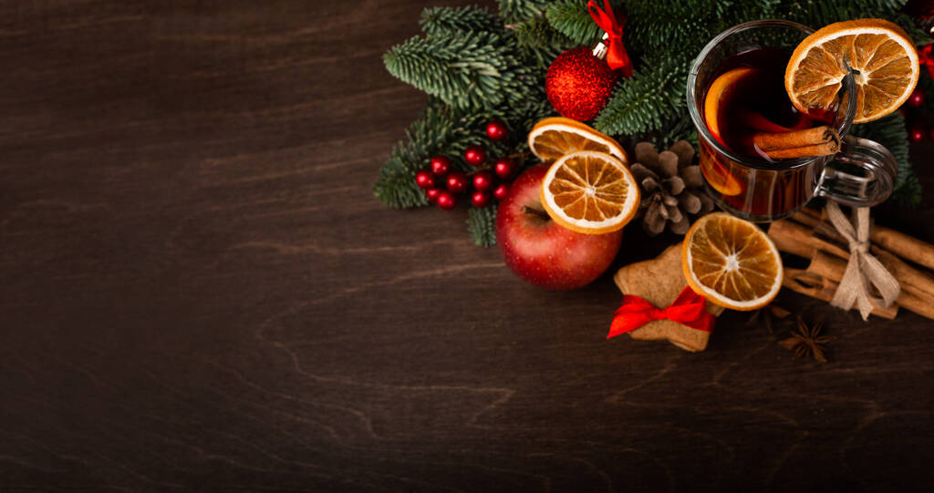 Vinho amontoado com paus de canela ramo de abeto laranja e bugigangas composição de Natal sobre fundo de madeira escura - Foto, Imagem