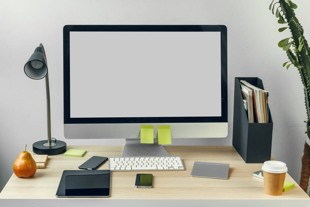 Компьютерный монитор с макетом белого экрана на офисном столе с принадлежностями - Фото, изображение