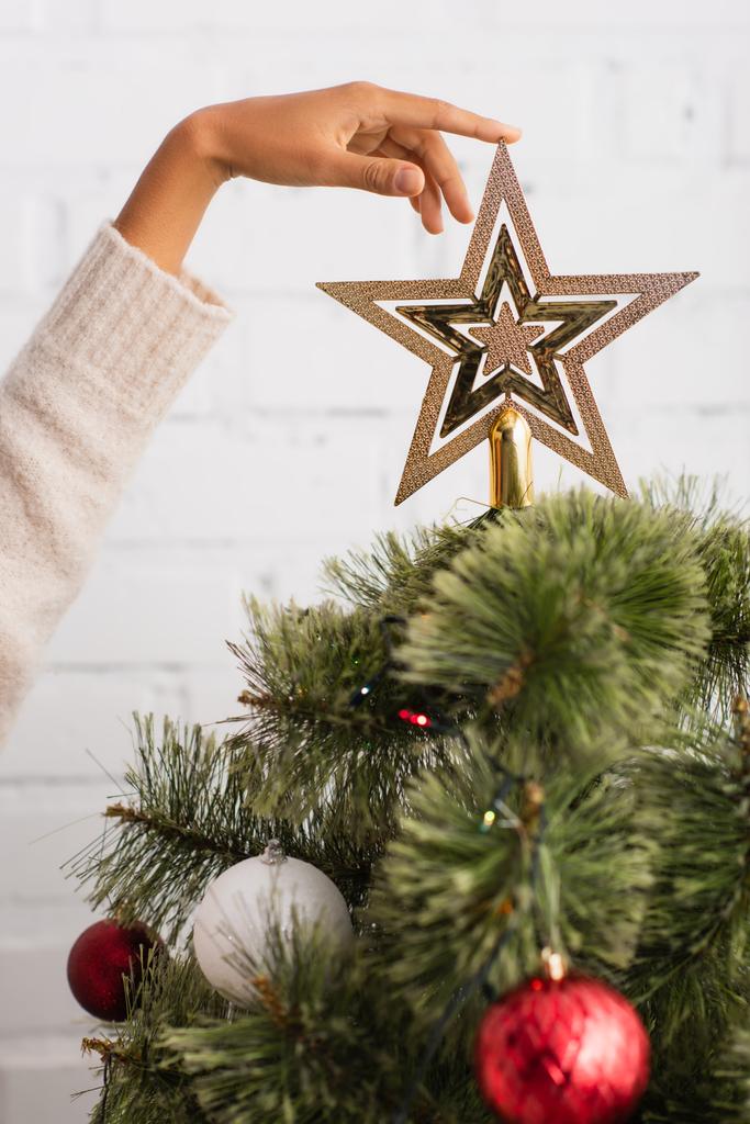 Ausgeschnittene Ansicht einer Afroamerikanerin, die einen Stern am Weihnachtsbaum berührt  - Foto, Bild
