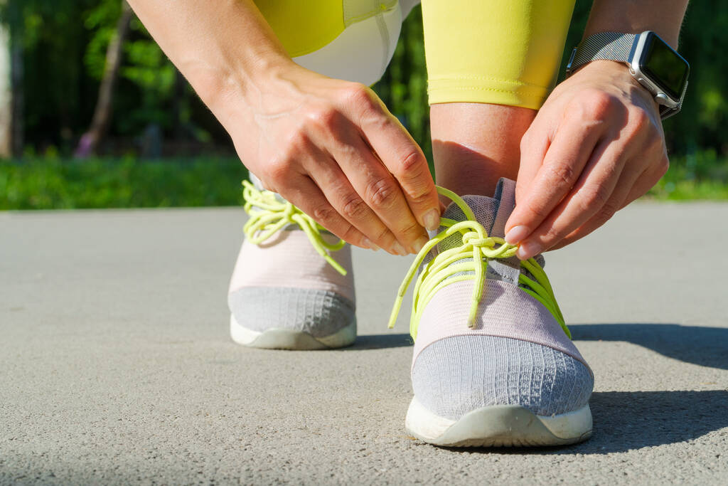 Vrouw runner binden haar schoenen veters voorbereiden voor een ochtend run - Foto, afbeelding