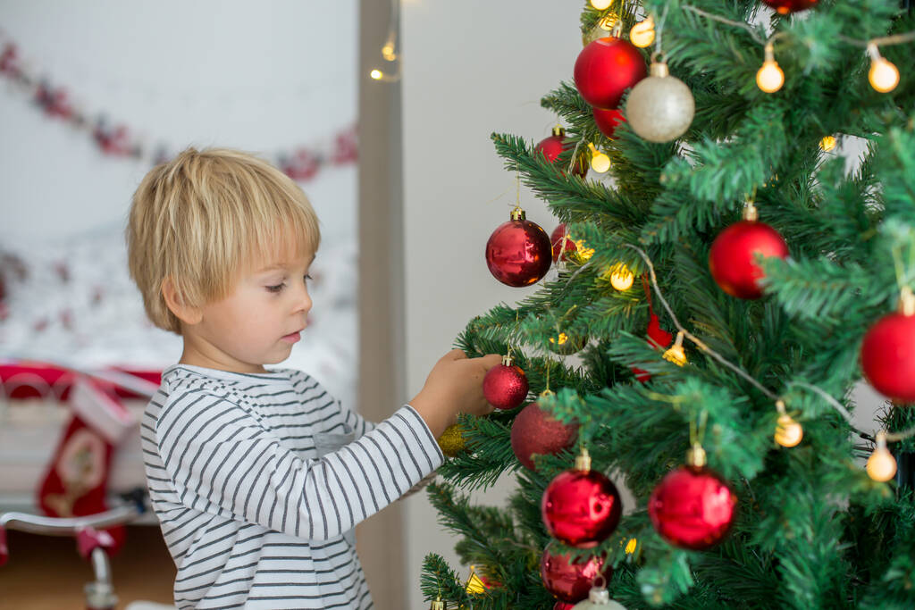 Bellissimo bambino bambino, decorare l'albero di Natale a casa, presenta sotto gli alberi - Foto, immagini