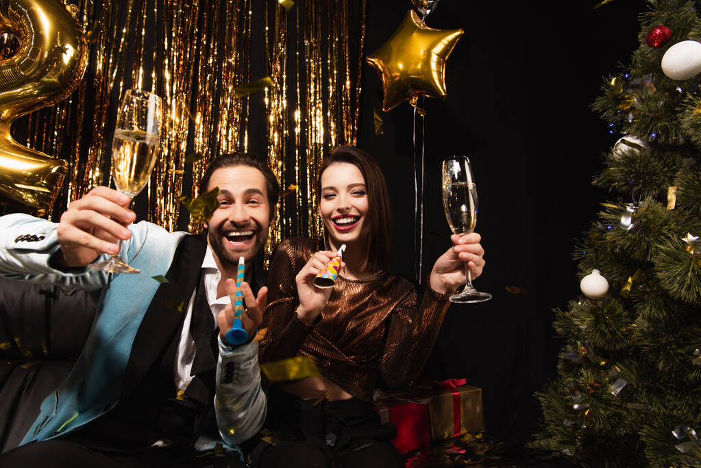 innoissaan pari samppanjaa ja puolueen sarvet katsot kameraa lähellä kiiltävä joulukoristeen musta - Valokuva, kuva