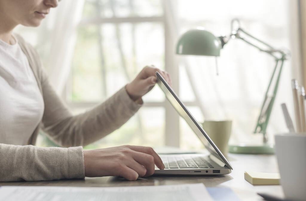 Mulher sentada na mesa e trabalhando em casa, ela está levantando a tampa do laptop - Foto, Imagem