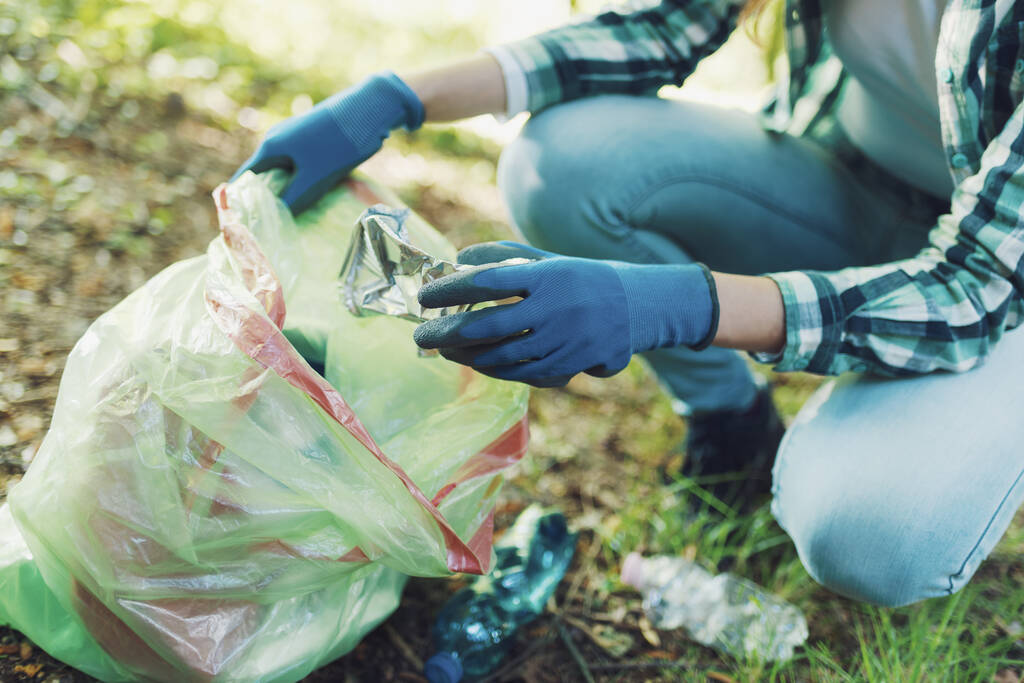 Εθελοντής καθαρισμού που συλλέγει σκουπίδια στο δάσος και κρατάει μια σακούλα σκουπιδιών, έννοια περιβαλλοντικής προστασίας - Φωτογραφία, εικόνα