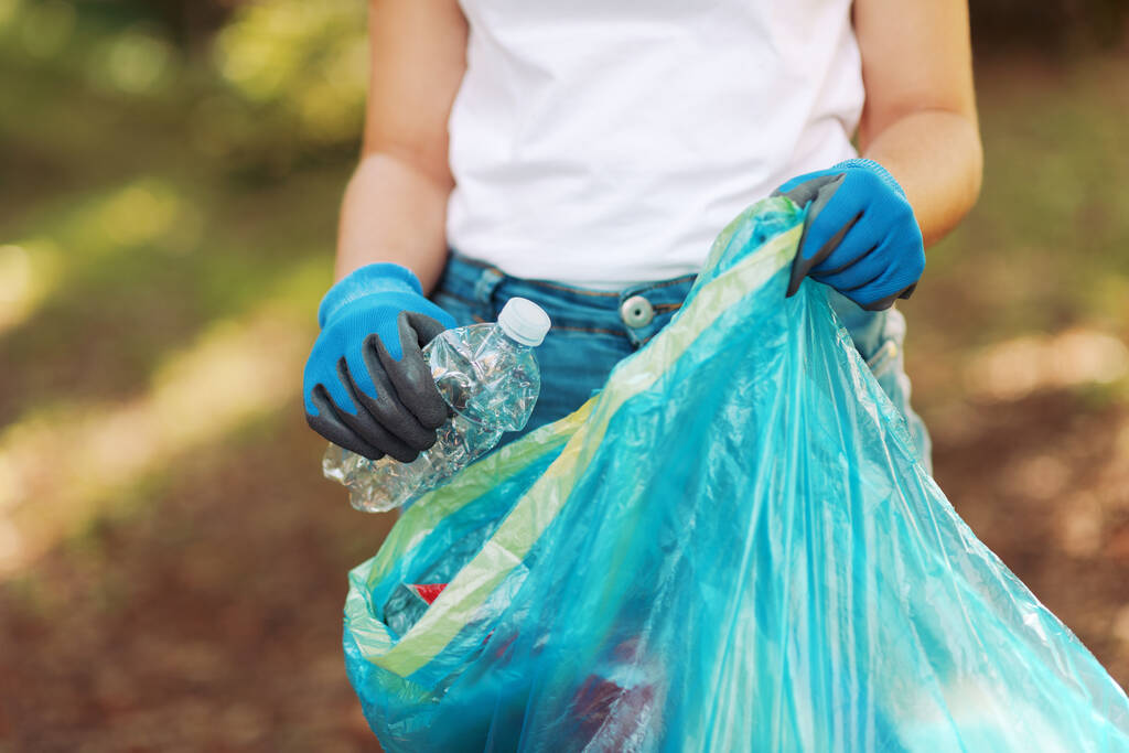 Wolontariuszka sprzątająca z workiem na śmieci i zbierająca śmieci w lesie - Zdjęcie, obraz