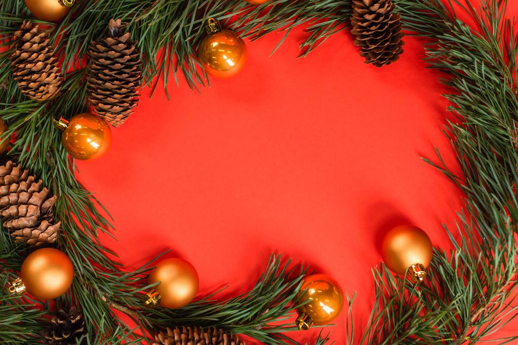 vista superior de conos de pino cerca de ramas verdes con bolas de Navidad en rojo - Foto, imagen