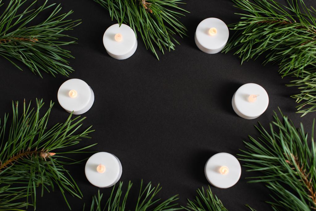 Ansicht von Kerzen und Tannenzweigen auf schwarz - Foto, Bild