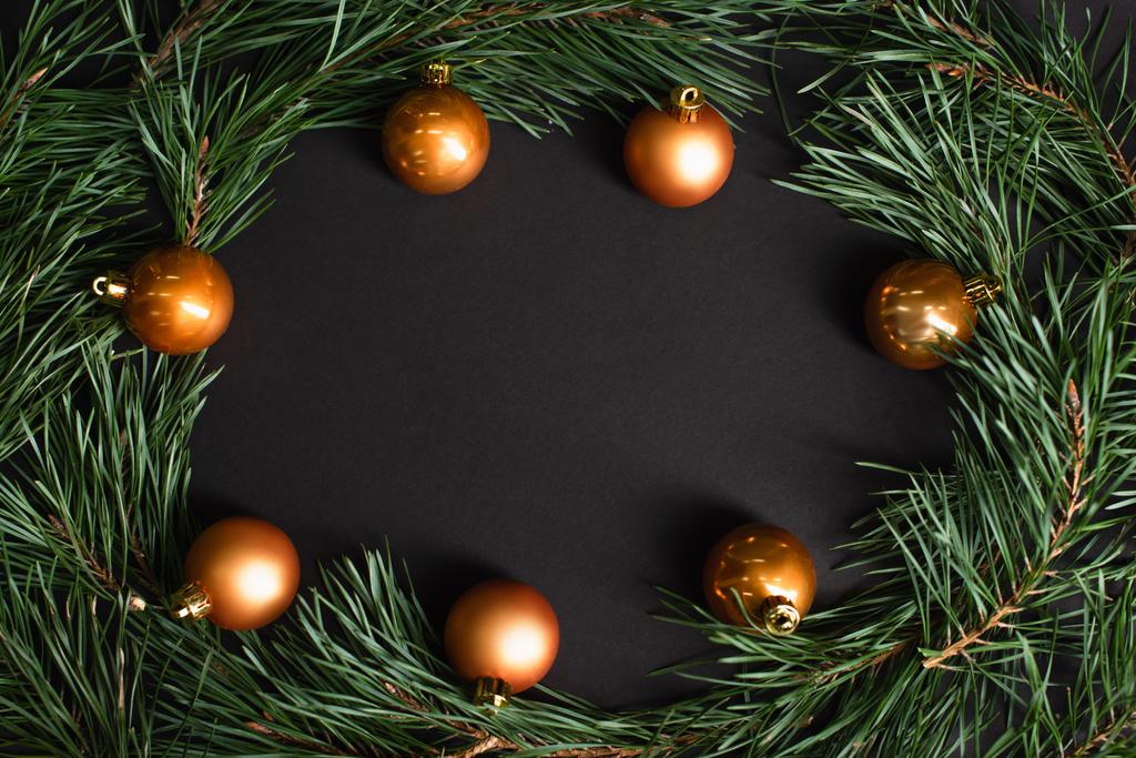 Плоский лежал с золотыми рождественскими шарами возле елки ветвей на черном - Фото, изображение