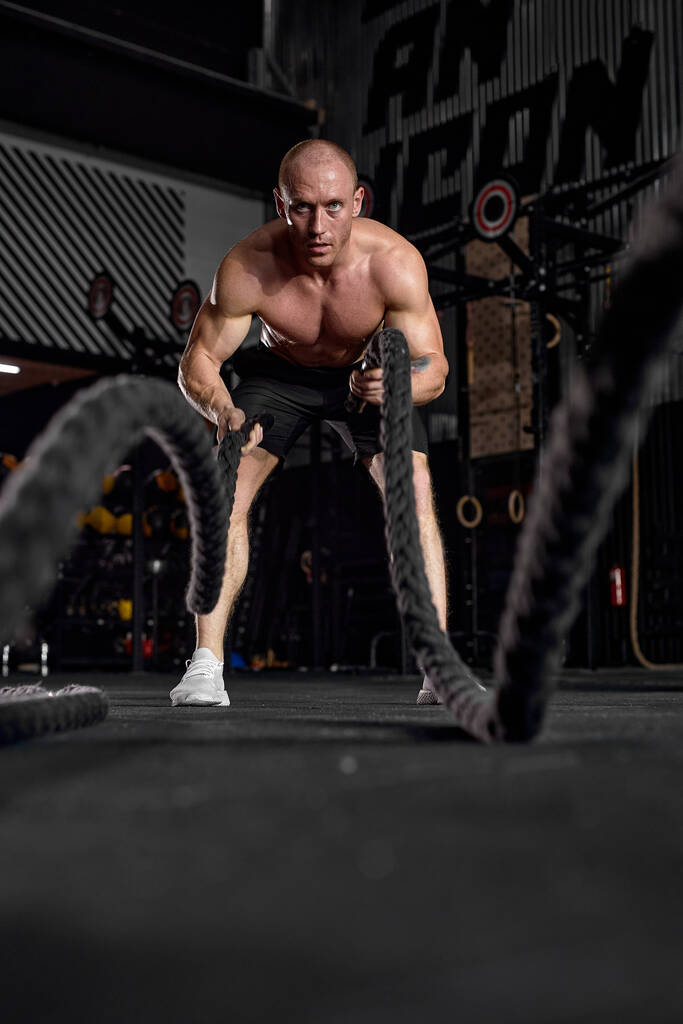 Erőhullámok. Erős kaukázusi testépítő sportoló edzés csatakötéllel - Fotó, kép