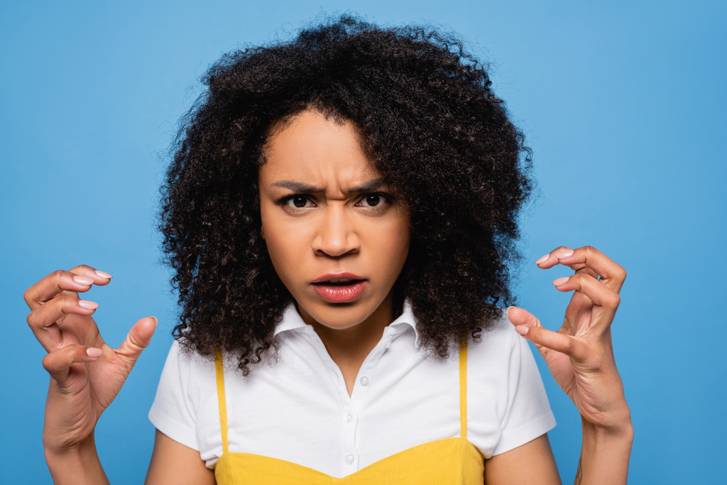 irritated african american woman showing scary gesture at camera isolated on blue - Photo, Image