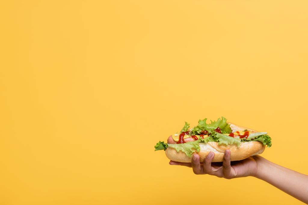 vágott kilátás afro-amerikai nő ízletes hot dog izolált sárga - Fotó, kép
