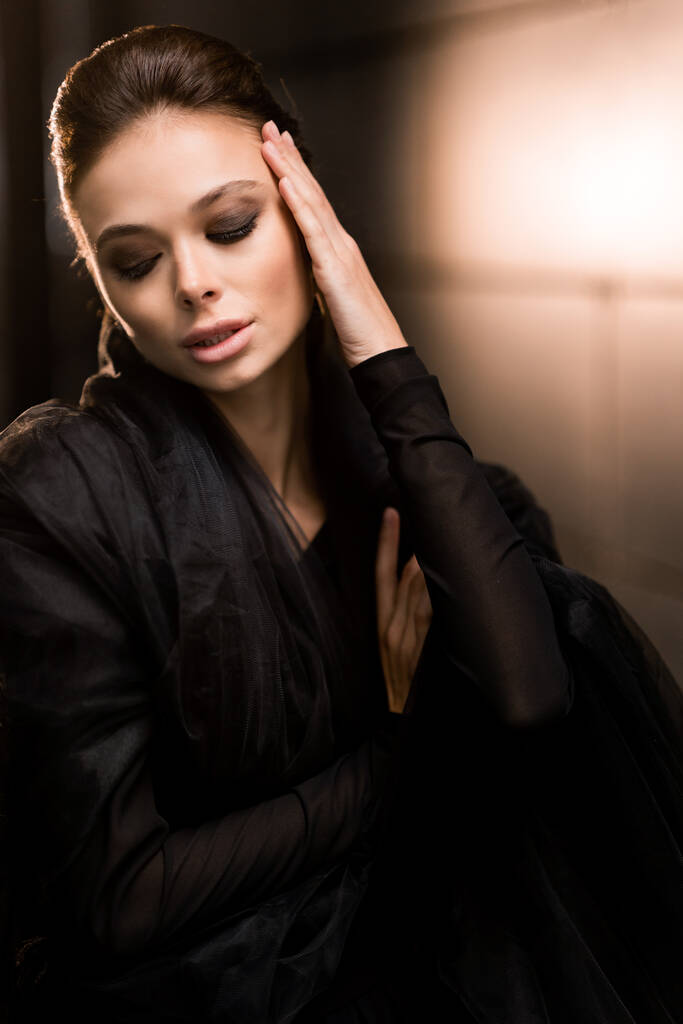 μυστηριώδης νεαρή γυναίκα με μαύρο φόρεμα που ποζάρει - Φωτογραφία, εικόνα