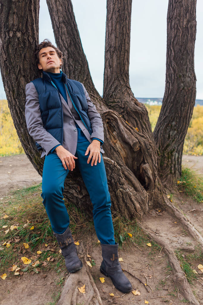 Hombre guapo alto de pie cerca del árbol en el bosque amarillo de otoño - Foto, Imagen