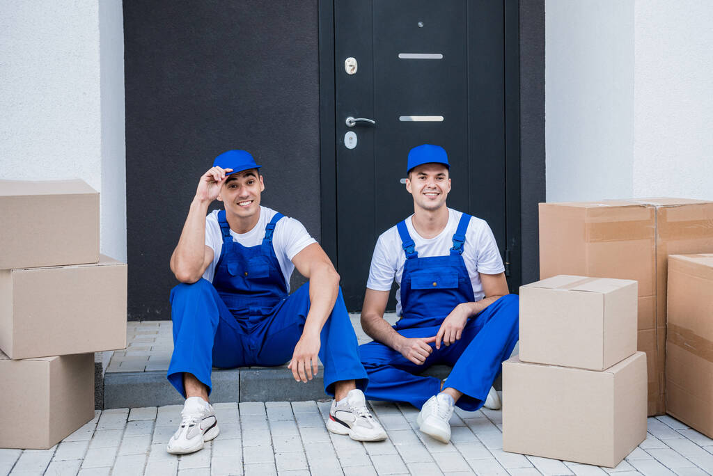 Two removal company workers have a break while sitting on the step - Photo, Image