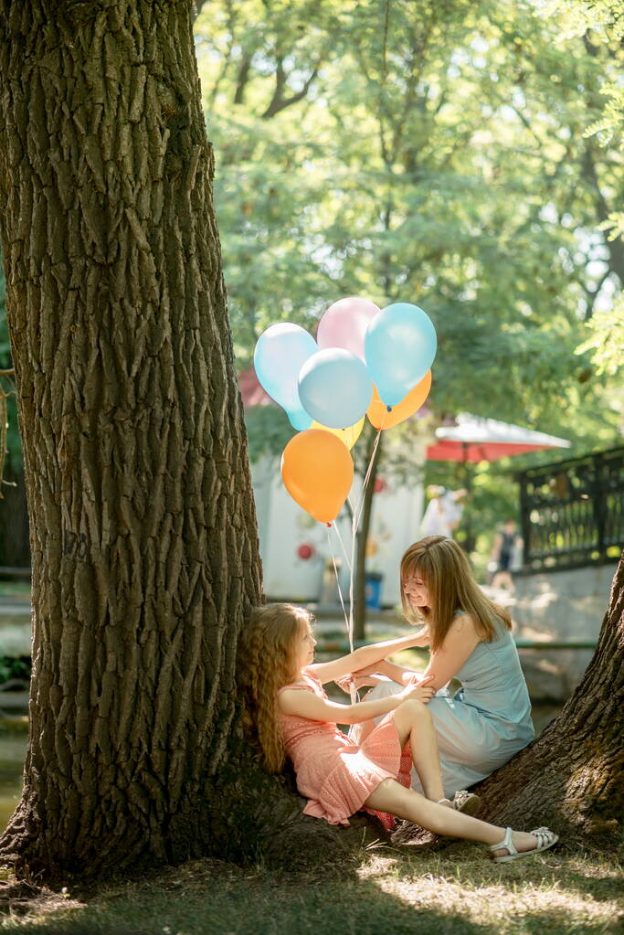 Mignonne maman familiale et sa fille lancent des ballons pour la célébration de l'anniversaire dans le parc d'été - Photo, image