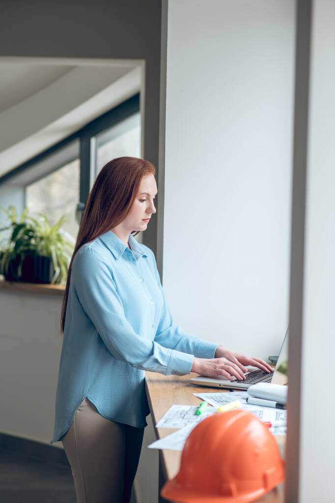 Frau arbeitet an Laptop, der neben Fenster steht - Foto, Bild