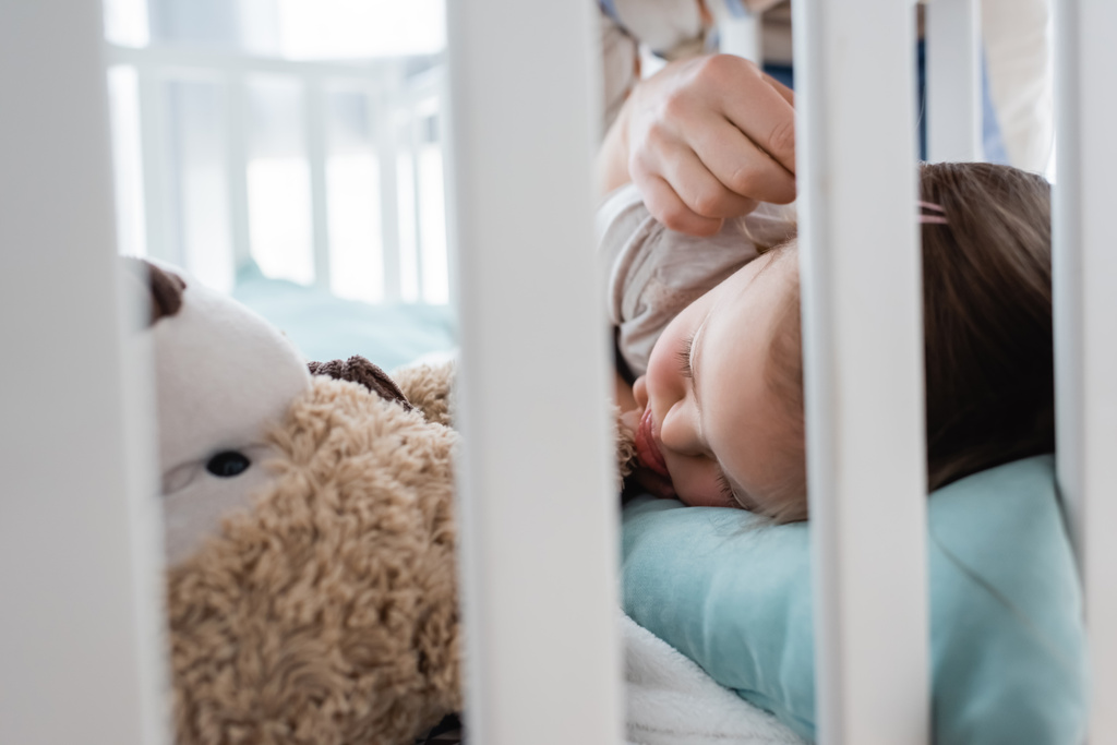 Родитель трогает спящую дочь с синдромом Дауна в кроватке дома  - Фото, изображение
