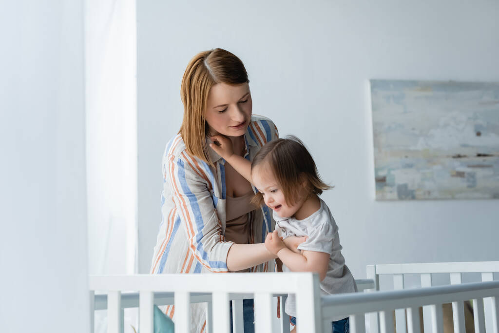 Anya gazdaság baba lefelé szindróma közelében bölcső otthon  - Fotó, kép