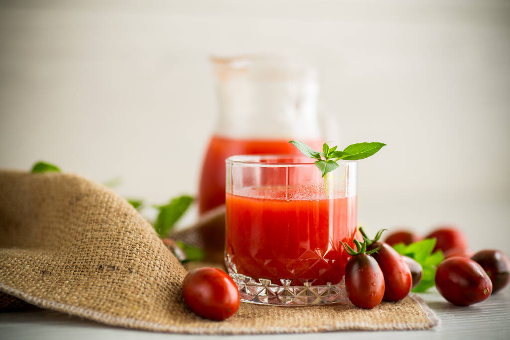 zelfgemaakt vers geperst tomatensap met pulp in een glazen karaf, op een houten tafel. - Foto, afbeelding