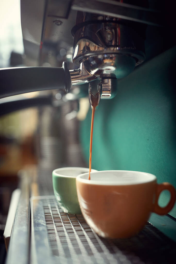 Κοντινό πλάνο ενός φλιτζανιού γεμίσματος με ζεστό καφέ σε καφετιέρα - Φωτογραφία, εικόνα