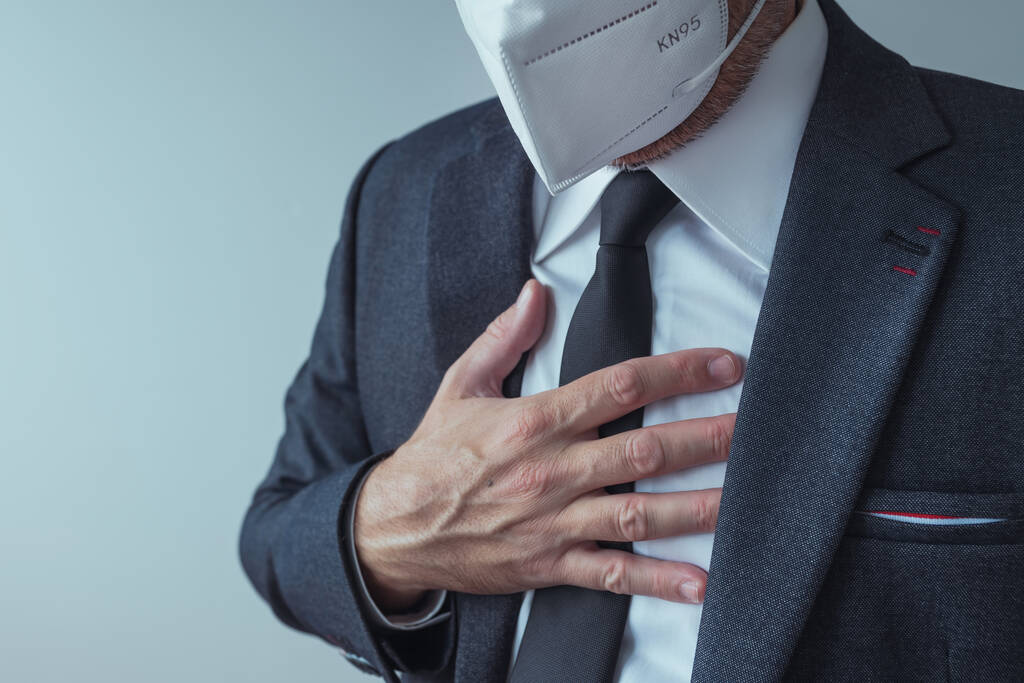 Κομψός επιχειρηματίας με προστατευτική αναπνευστική μάσκα KN95 με σοβαρά συμπτώματα πόνου στο στήθος, επιλεκτική εστίαση - Φωτογραφία, εικόνα