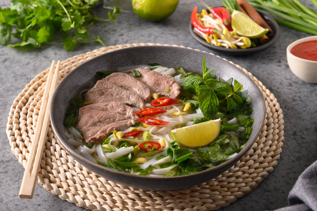 Pho Bo Soup with beef in gray bowl on gray. Vietnamese cuisine. - Photo, Image