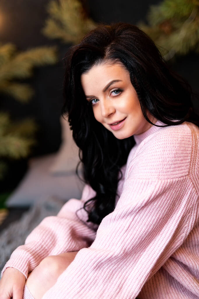 Pretty woman posing to the camera while looking dreamy. Pink sweater on a nice girl. New year decorations. Holidays concept - Photo, Image