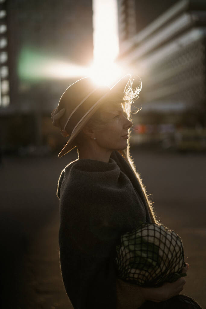Mulher de meia-idade bonita em um chapéu com um corte de cabelo curto no centro de uma cidade grande. Retrato de close-up, luz de fundo suave. - Foto, Imagem