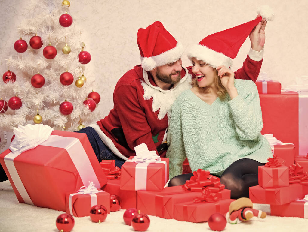 Щаслива родина святкує Різдво. Концепція різдвяних подарунків. Пара закоханих насолоджується святкуванням Різдва. Пара носить капелюхи як різдвяний фон Санти Клауса. Легко розповсюдити щастя навколо
 - Фото, зображення
