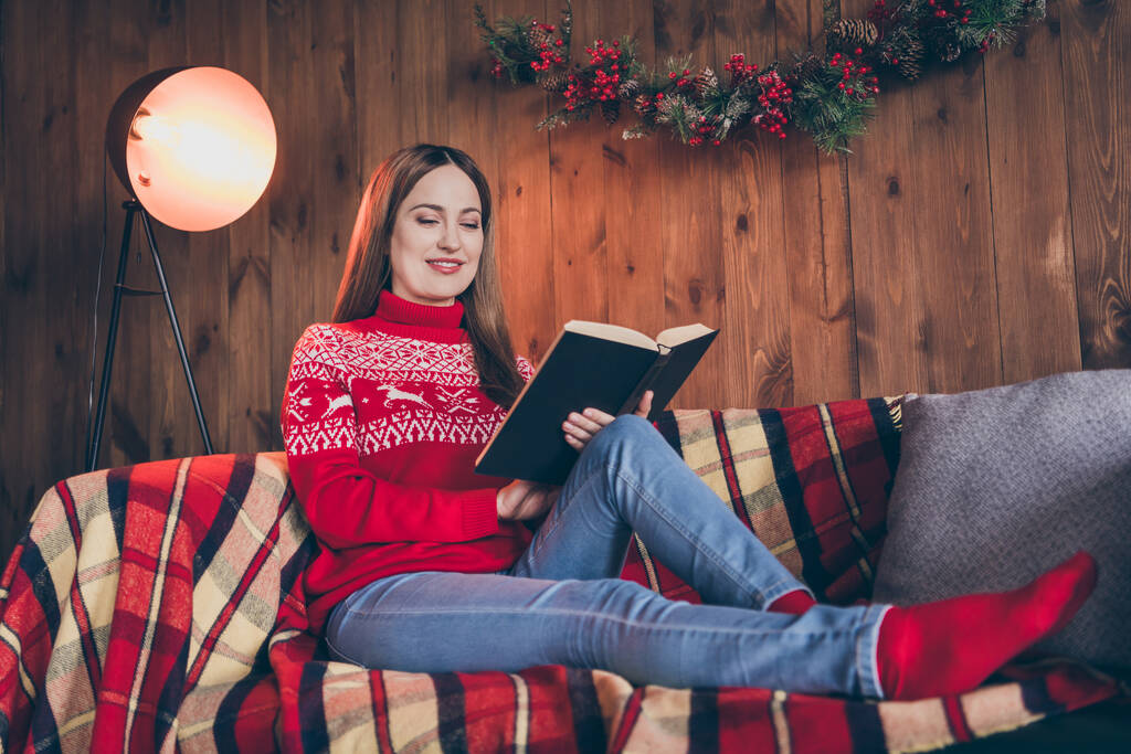 Fénykép álmodozó fényes fiatal nő öltözött piros pulóver olvasás újévi történetek mosolygós beltéri szoba ház - Fotó, kép