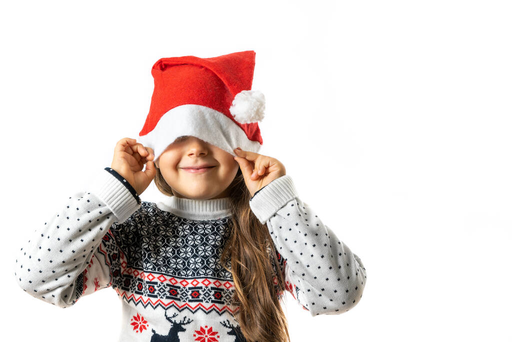 muotokuva söpö tyttö valkoinen neulottu joulupusero poro piilossa puoli kasvot Santa Claus hattu, eristetty valkoisella taustalla - Valokuva, kuva