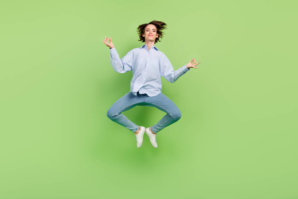 Full body photo of cheerful young calm happy woman jump up asana yoga isolated on green color background - Photo, Image