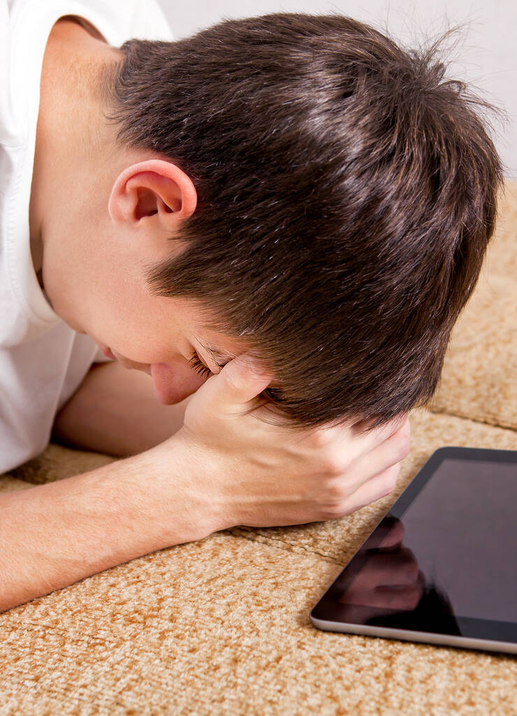 Sad Young Man z komputera typu Tablet w domu zbliżenie - Zdjęcie, obraz