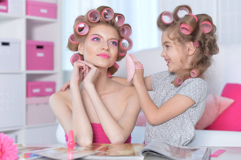 портрет щасливої матері і маленької дочки з ліфчиками для волосся вдома читання журналу
 - Фото, зображення