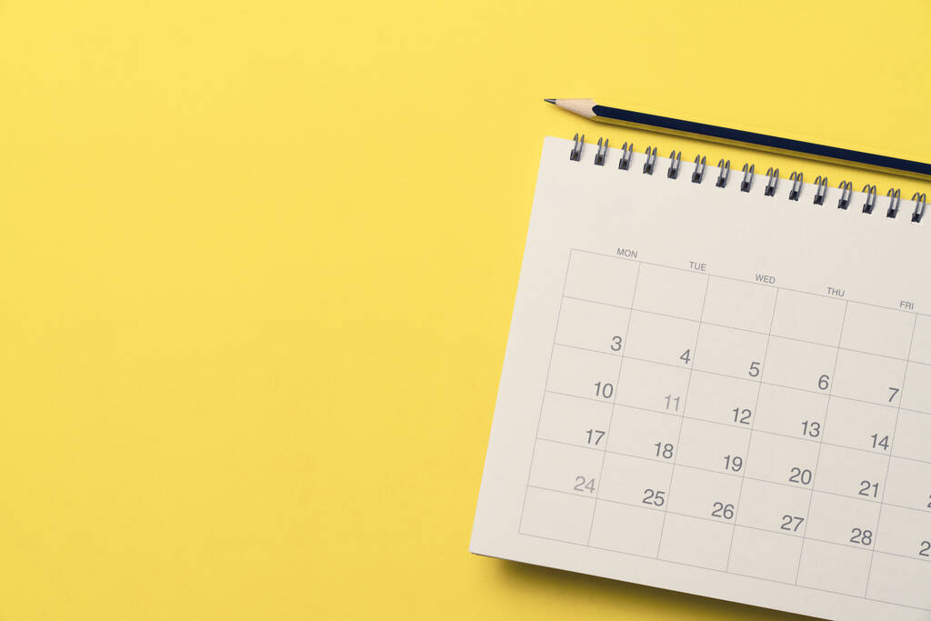 primer plano del calendario y lápiz sobre el fondo de la mesa amarilla, planificación de reuniones de negocios o concepto de planificación de viajes - Foto, imagen