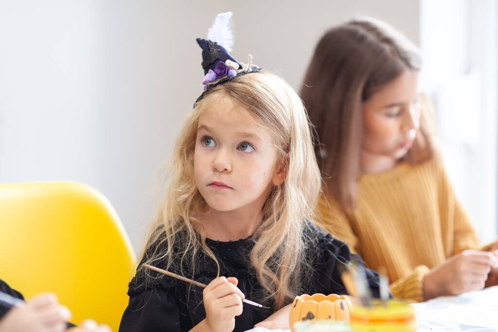Bir çocuk Cadılar Bayramı için saksıyı balkabağı şeklinde boyar.. - Fotoğraf, Görsel