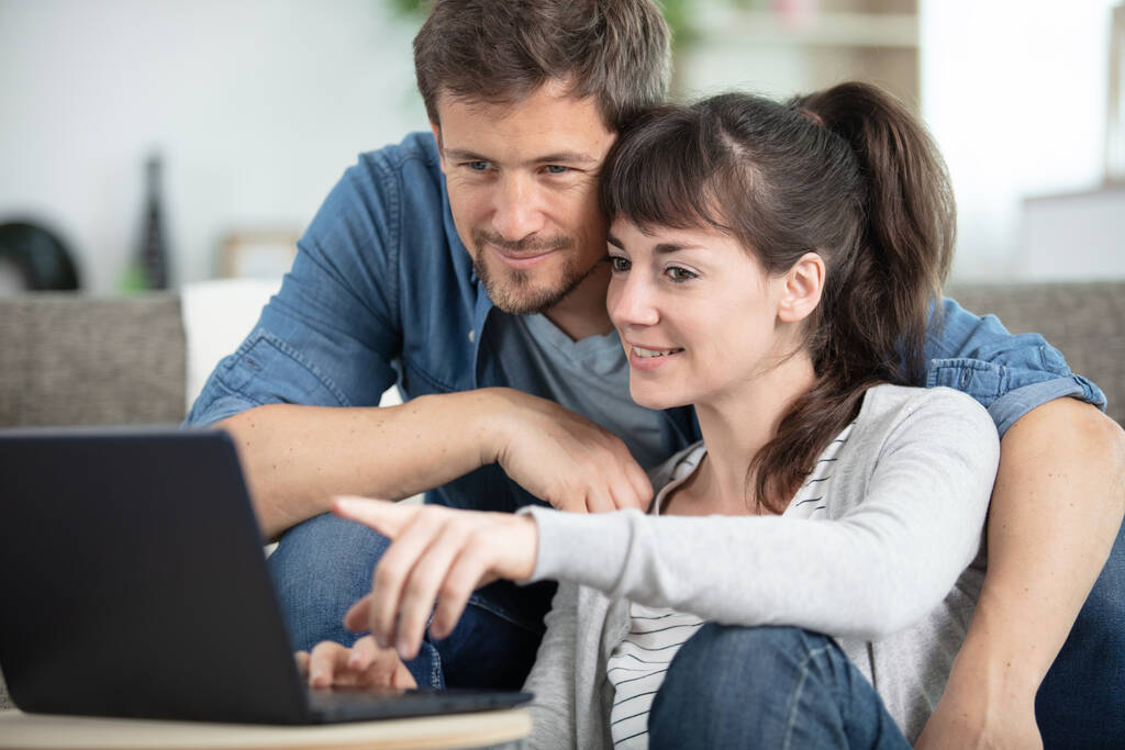 Счастливая пара с ноутбуком проводит время вместе дома - Фото, изображение