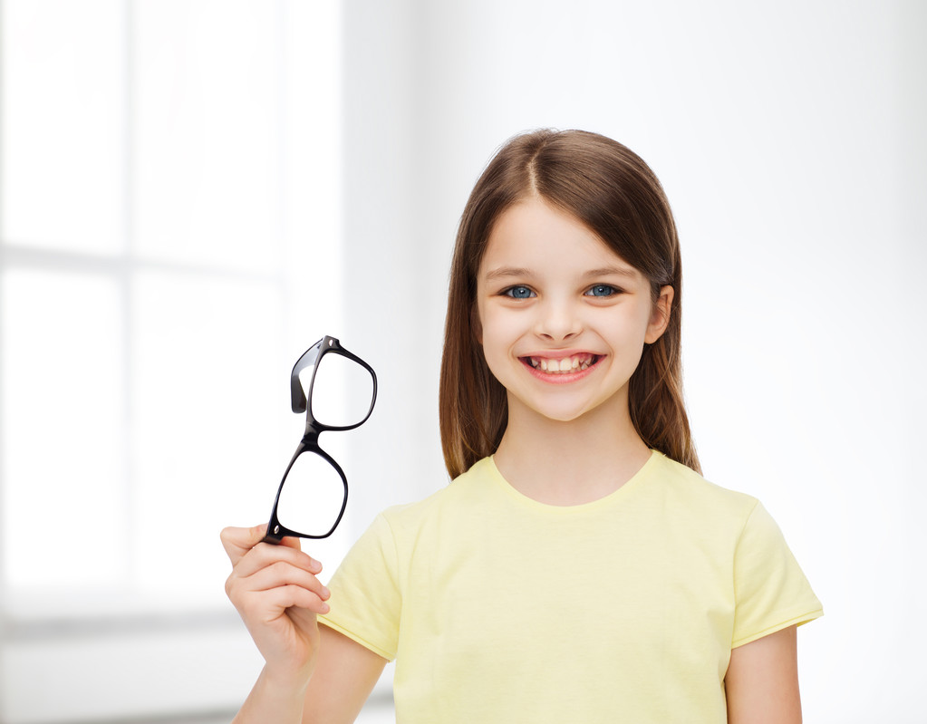 χαμογελώντας χαριτωμένο κοριτσάκι που κρατάει τα μαύρα γυαλιά - Φωτογραφία, εικόνα