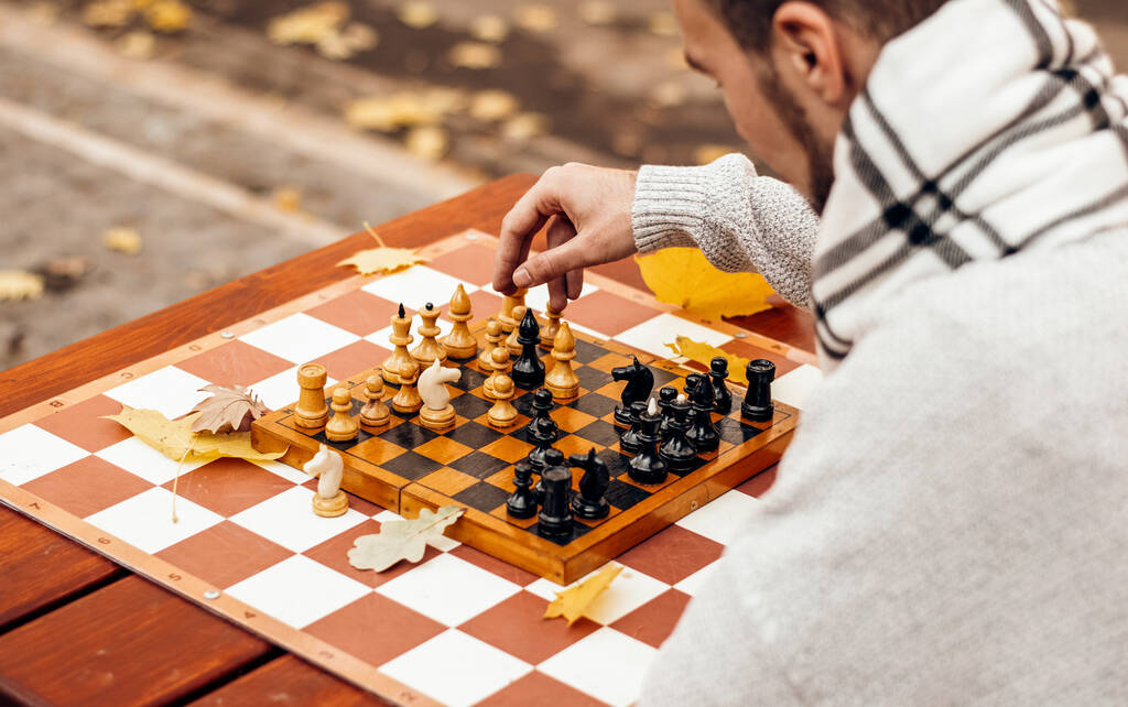 Top view: Bir adam oyun alanındaki sonbahar parkında bir masada satranç oynuyor - Fotoğraf, Görsel